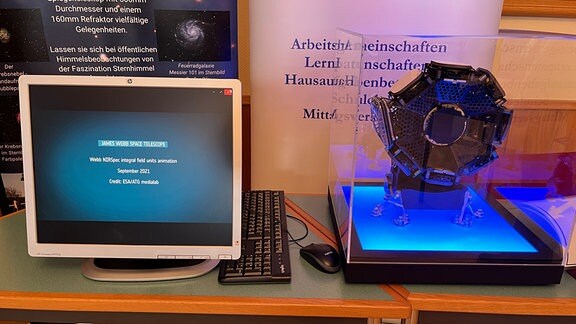 Ein Computerbildschirm und eine rundliche technische Anlage stehen auf einem Tisch