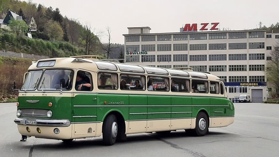 Ein grün-weißer Oldtimerbus der Marke "Ikarus 55" steht vor dem alten MZ-Werk in Zschopau.