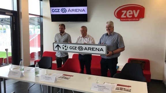 Toni Wachsmuth (Sportdirektor FSV Zwickau), Rainer Kallweit (Geschäftsführer der Stadion Zwickau Betriebsgesellschaft) und Thomas Frohne (Geschäftsführer der Gebäude- und Grundstücksgesellschaft Zwickau) halten ein Hinweisschild mit dem Namen "GGZ-Arena" in den Händen