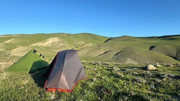Zwei Zelte vor dem Hintergrund einer Berglandschaft.