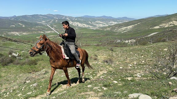 Ein junger Mann reitet auf einem Pferd.