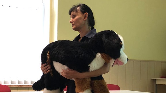 Eine Frau (Ina Dunger, DRK Zwickau) hält einen sehr großen Plüschhund auf dem Arm.