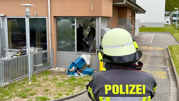 Ein Polizist geht auf ein beschädigtes Haus zu