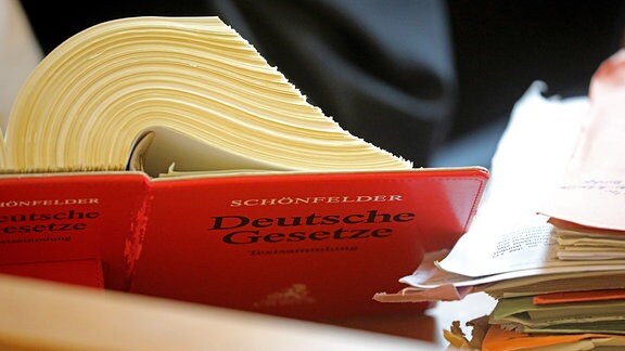 Ein Anwalt sitzt im Landgericht vor einem Textband "Deutsche Gesetze"