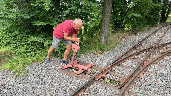 Ein Mann stellt die Weichen der Parkeisenbahn.