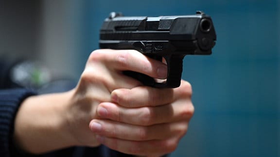 Ein Polizist hält eine Pistole vom Typ Walther P99 in den Händen