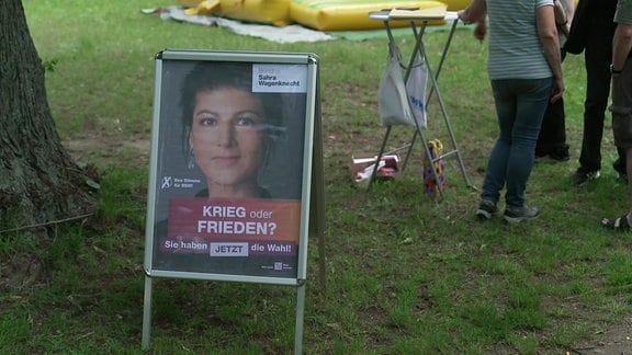 Ein Plakat mit dem Gesicht einer Frau auf einem Aufsteller auf einer Wiese