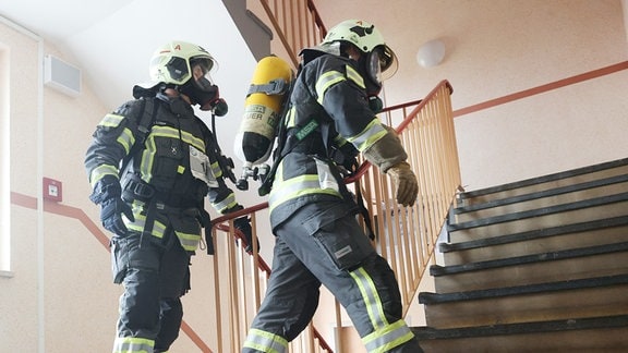 Feuerwehrmänner mit Atemschutzmaske und Sauerstoffflasche rennen eine Treppe hoch beim 10. Zwickauer Hochhaus-Treppenlauf und 5. Feuerwehr-Treppenlauf. 