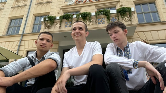 Drei Jungen sitzen auf der Treppe vor dem Rathaus von Zwickau