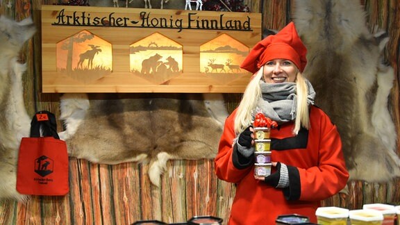 Sarel Okonen, eine finnische Hogihändlerin, steht mit roter Mütze an ihrem Stand.