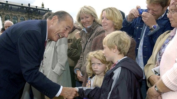 Der französische Staatspräsident Jacques Chirac begrüßt am 04.09.2003 in Dresden bei einem Spaziergang durch die Gartenanlage des Zwingers wartende Kinder.
