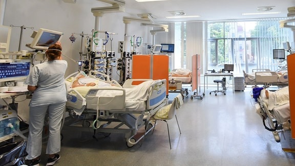 Auf der Intensivtherapie-Station (ITS) im Klinikum St. Georg steht eine Mitarbeiterin am Bett einer Patientin.
