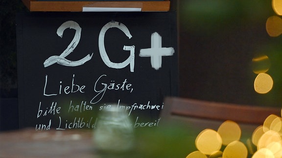 Ein Schild an der Eingangsür weist auf die 2G+ Regel in einem Restaurant hin. 