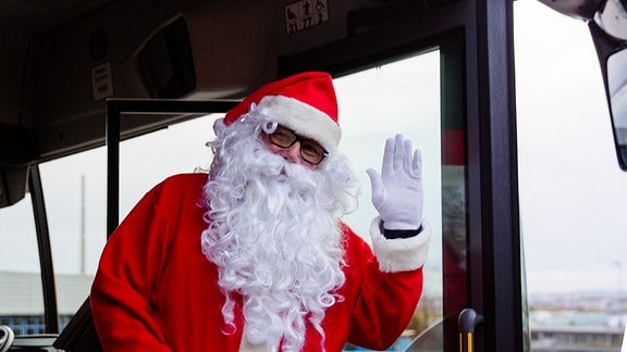 Ein Weihnachtsmann steht im Bus und winkt.