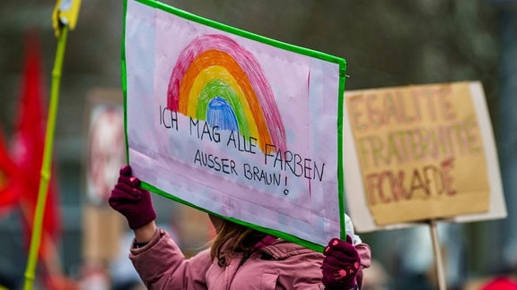 Ein Plakat „Ich mag alle Farben außer Braun!“ wird auf einer Kundgebung gegen Rechtsextremismus vor dem Rathaus hochgehalten.