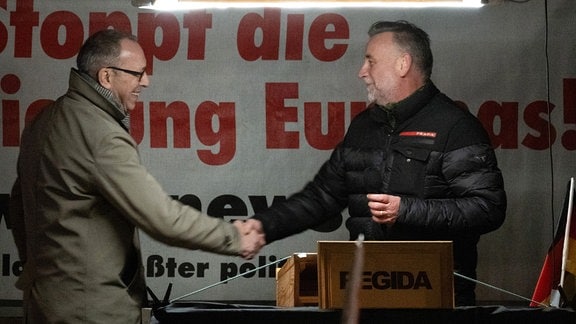 Jörg Urban (l), Vorsitzender der AfD Sachsen, wird auf einer Kundgebung der rechtsextremistischen Bewegung Pegida von dem Gründer der Bewegung, Lutz Bachmann, auf der Bühne begrüßt.