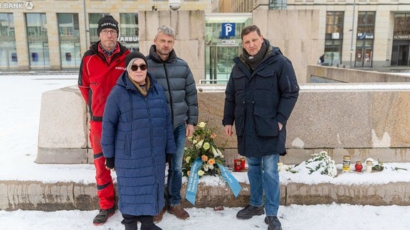 Vier Menschen stehen an einer Gedenkstelle
