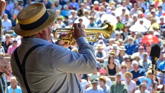 Ein Trompeter spielt vor zahlreichen Zuschauern.