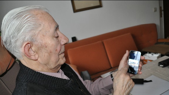 Ein alter Mann bedient ein Smartphone
