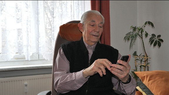 Ein alter Mann bedient ein Smartphone.