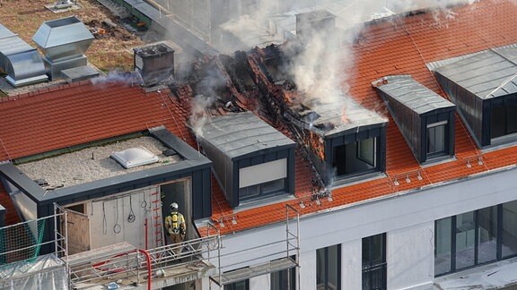 Eine Einsatzkraft der Feuerwehr befindet sich in einem Haus, das brennt.