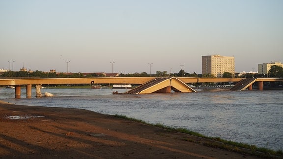 Eine eingestürzte Brücke liegt in einem Fluss, der Hochwasser führt. 