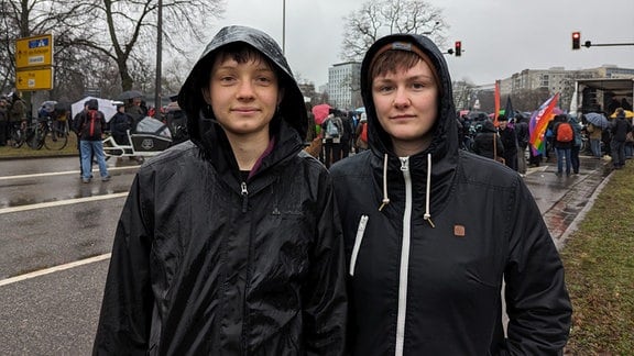 Zwei junge Frauen bei Regenwetter auf einer Demo 