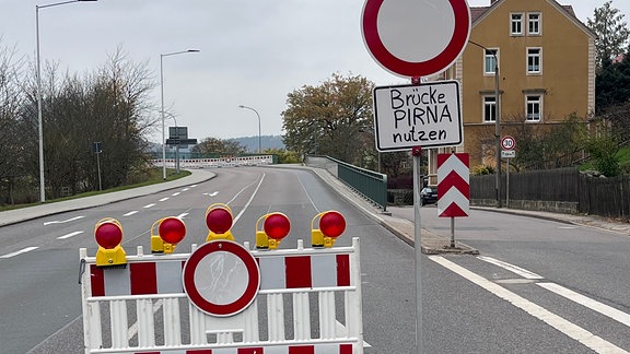 Ein Verbotsschild steht vor der gesperrten Elbbrücke von Bad Schandau. "Brücke Pirna nutzen" wurde mit Edding darauf geschrieben.