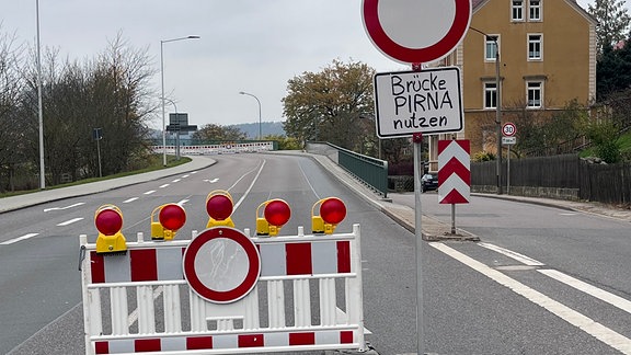 Ein Verbotsschild steht vor der gesperrten Elbbrücke von Bad Schandau. "Brücke Pirna nutzen" wurde mit Edding darauf geschrieben.