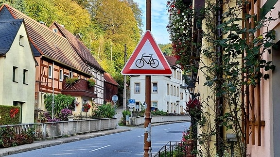 Am Rand einer engen Straße steht ein Verkehrsschild mit dem Hinweis: Achtung, Radfahrer!