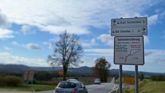 Auf einer Landstraße in der Sächsischen Schweiz weist ein Verkehrsschild auf zwei verschiedene Radverkehrsführungen hin.