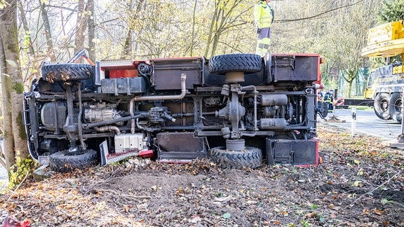 Ein recht neues Spezialfahrzeug der Feuerwehr liegt auf der Seite im Wald. Man sieht nur die vielen Räder un den Unterboden.