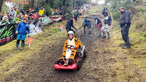 Ein kostümierter Mann fährt mit einem Go-Kart einen Berg hinunter.