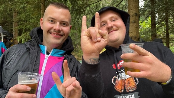 Zwei junge Männer trinken in ausgelassener Stimmung ein Bier.