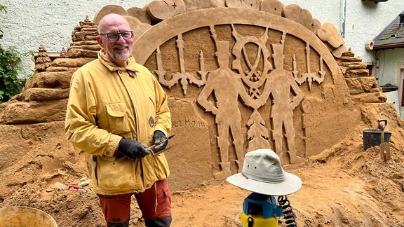 Ein Mann vor einer Sandskulptur
