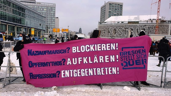 Menschen halten ein Plakat hoch und ehren sich gegen NPD-Leute und rechte Demonstranten, die am 13.2.2021 das Kriegsgedenken in Dresden vereinnahmen wollen.