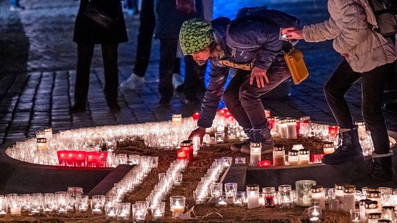 Menschen formen mit ihren Lichtern eine große Kerze auf dem Neumarkt in Dresden