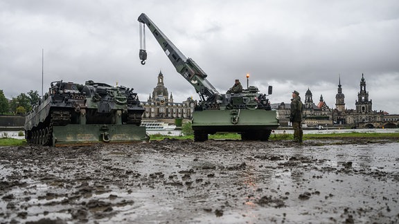 Zwei Bergepanzer 3 der Bundeswehr, auch «Büffel» genannt, stehen vor der historischen Altstadtkulisse neben der eingestürzten Carolabrücke, um im Fall eines Hochwassers Baumaschinen zu bergen.