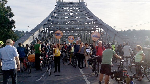 Menschen protestieren auf einer Brücke für einen Radweg.