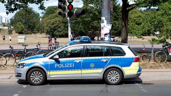 Während einer Demonstration im Dresdner Alaunpark steht ein Polizeifahrzeug auf einem Fußgängerüberweg und vor einer Ampel.