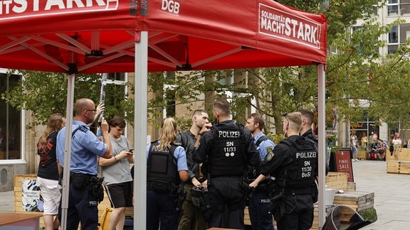 Polizisten stehen am Infostand des Deutschen Gewerkschaftsbundes in Dresden.