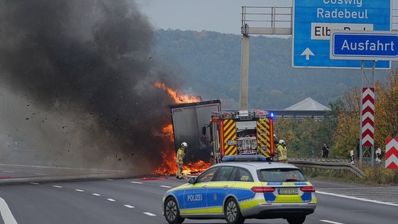 Ein brennender Lkw wird von Feuerwehrleuten gelöscht.