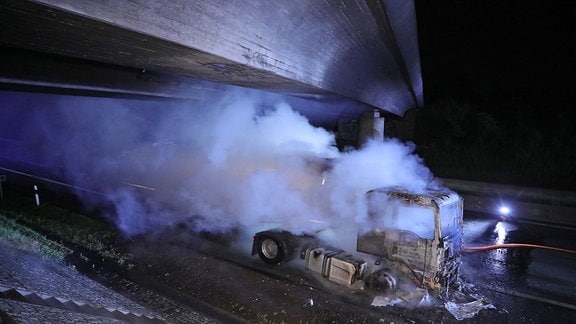 Ein Laster steht unter der Autobahnbrücke inmitten einer riesigen Rauchwolke.