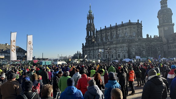 Menschen stehen auf dem Theaterplatz in Dresden.