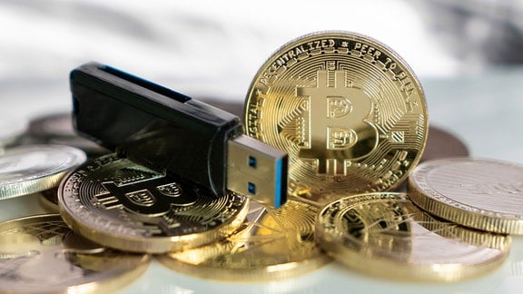 Bitcoin.Goldmünzen neben einem USB Stick.