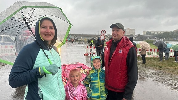 Menschen mit Regenschirmen vor eingestürzter Carolabrücke.