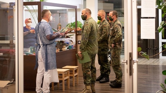 Drei Soldaten im Gespräch mit Mitarbeitern eines Pflegeheims