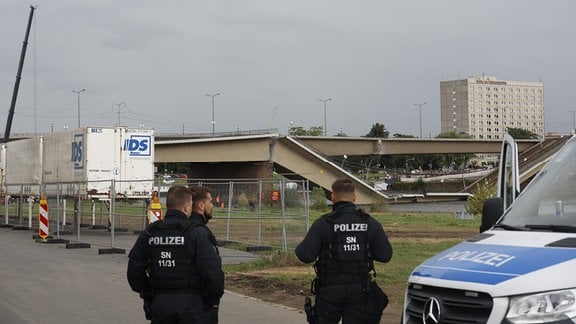 Polizisten stehen vor der kaputten Carolabrücke.