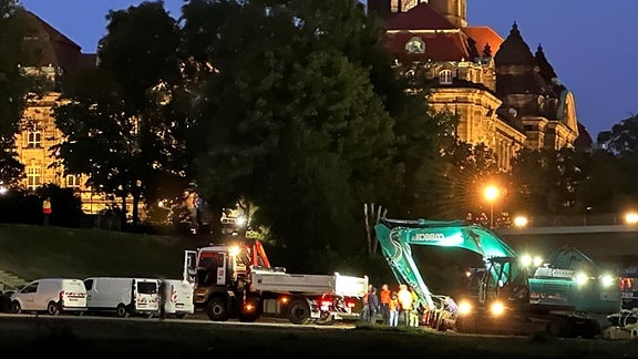 Bagger und Lkw von Abrissfirmen stehen im abendlichen Dunkel in Dresden bereit, Abrissarbeiten vorzunehmen.