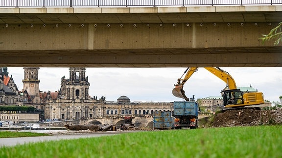 Ein Bagger belädt eine LKW mit Schutt der teileingestürzten Carolabrücke, im Hintergrund ist die Altstadt zu sehen.